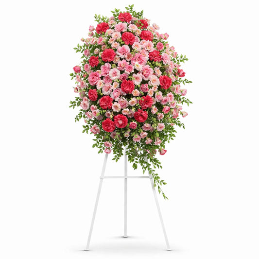 Pink and fuchsia rose funeral standing spray on white easel